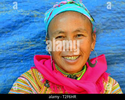 Mature Vietnamese Flower H'mong woman wears a colourful traditional Flower H'mong costume with large tribal silver earrings. Stock Photo