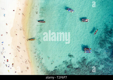 View from above, aerial view of a beautiful tropical beach with white sand and turquoise clear water, long tail boats and people sunbathing. Stock Photo