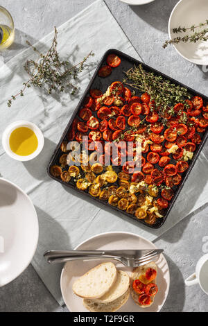 Baked juicy cherry tomatoes into baking tray on concrete background top view Stock Photo