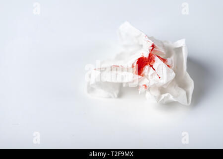 A photo of used bloody toilet paper on the light blue background. Menstrual or hemorrhoids bleeding