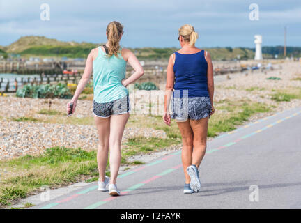 Pair of women walking along the seafront promenade in Summer in the UK. Stock Photo