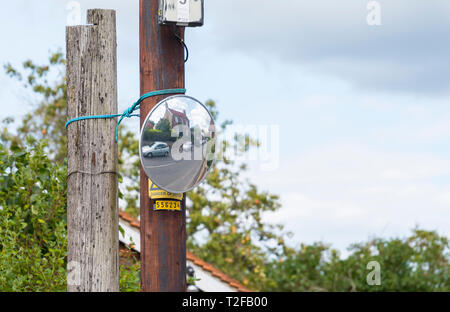 Convex mirror on a pole on a road in the UK to aid visibility at a blind junction. Stock Photo