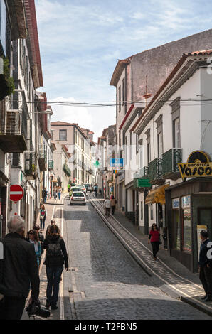 PONTA DELGADA, PORTUGAL - MAY 10, 2012: One of the typical narrow streets in the city center. People walk on the sidewalks lined with tile patterns Stock Photo