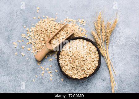 Rolled oats or oat flakes in bowl top view, concrete background. Healthy eating, dieting, weight loss concept Stock Photo