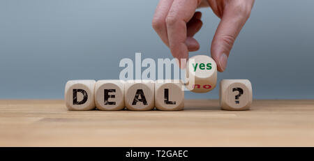 Deal or no deal? Hand turns a cube and changes the word 'no' to 'yes'. Stock Photo