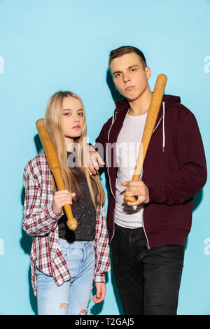 Sport games. Close up fashion portrait of two young cool hipster girl and boy wearing jeans wear. Woman and boy with baseball bat. Studio shot of two  Stock Photo