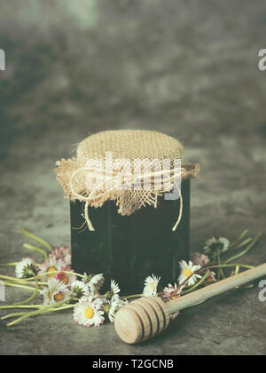 Honey in jar and daisies on Grunge background Stock Photo