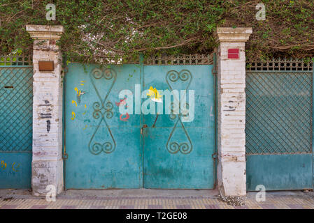 Background of three green old weathered grunge antique wrought iron gates with floral pattern ornaments and two white bricks columns Stock Photo