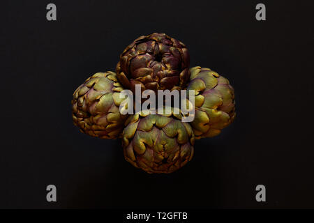 Group of 4 artichokes isolated from above over a black background flatlay concept Stock Photo