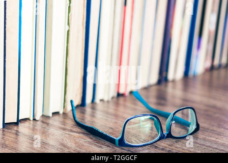 Hardback books on white wooden table, open book and glasses, copy space for text Stock Photo