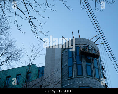 workers cleaning windows from cradle hanging in front of reconstructed office building. view from ground Stock Photo