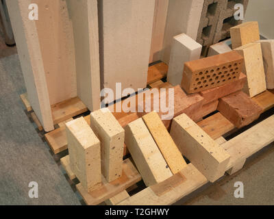 group of different samples of building bricks and concrete blocks on palette for sale. made from various modern materials Stock Photo