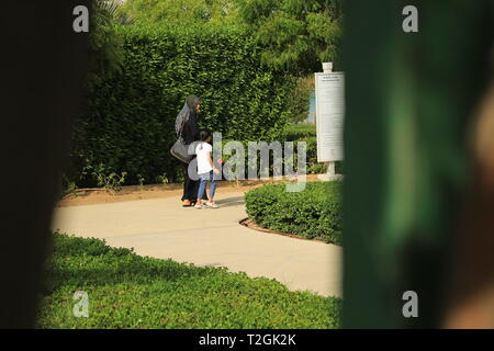 Mother and Daughter walking happy and Peaceful along a path surrounded by Green Bushes and Trees Stock Photo