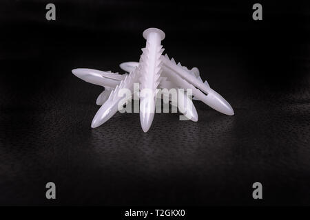 A group of plastic anchors on a black surface Stock Photo