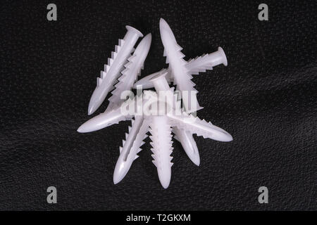 A group of plastic anchors on a black surface Stock Photo