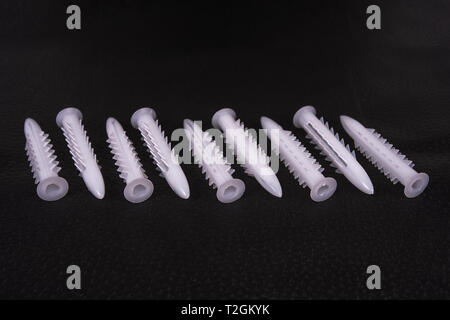 A group of plastic anchors organized in a row on a black surface Stock Photo