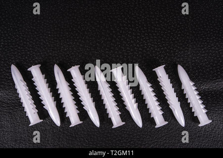 A group of plastic anchors organized in a row on a black surface Stock Photo