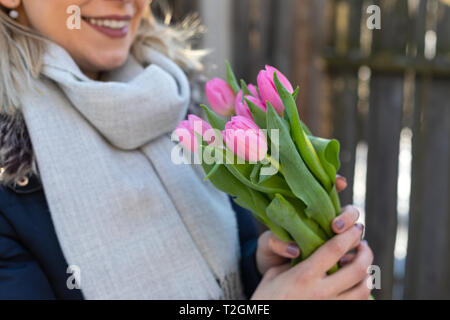 Close up picture of young lady holding a beautiful bouquet of pink tulips Stock Photo