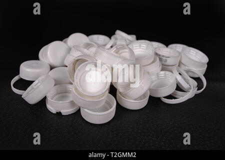 A group of used caps of plastic bottles on a black surface Stock Photo