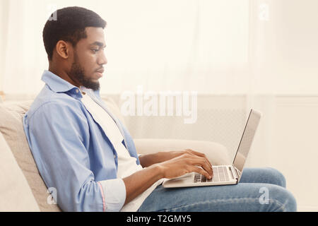 Recruitment concept. African-american guy browsing work opportunities online, using job search app or website on laptop, empty space Stock Photo