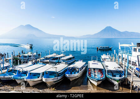 Panajachel, Lake Atitlan, Guatemala - December 23, 2018: Boats pulled up to beach with Toliman, Atitlan & San Pedro volcanoes on horizon in Panajachel