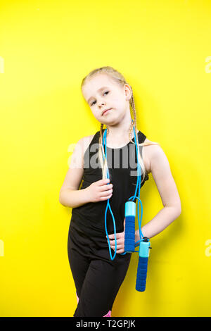 Theme sport and health. Beautiful caucasian child girl with pigtails posing  yellow background with smile. little athlete holds sport rope in hands. Ba  Stock Photo - Alamy