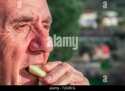 Close-up portrait of a senior of 70-79 years eating apple at outdoor, healthy lifestyle concept Stock Photo