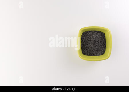 Poppy seeds in a ceramic plate isolated on wooden background. Selective focus Stock Photo