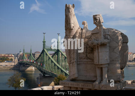 Statue of St Stephen outside the Cave Church, Gellert Hill, Budapest, Hungary, with the Liberty Bridge in the background. Stock Photo