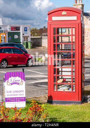 Old red telephone box converted to book lending library in conservation village, East Saltoun, East Lothian, Scotland, UK Stock Photo