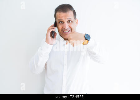 Middle age man calling using smartphone with surprise face pointing finger to himself Stock Photo