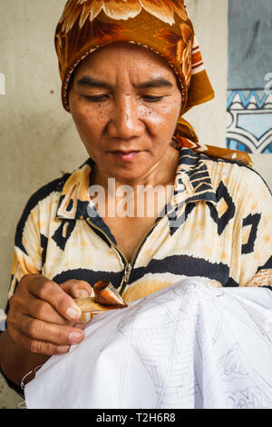 Portrait of a woman working on making a design on a handmade tablecloth Stock Photo