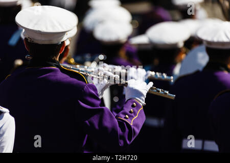 Closeup of musician in purple uniform playing shiny silver flute marching in Columbus Day Parade Stock Photo