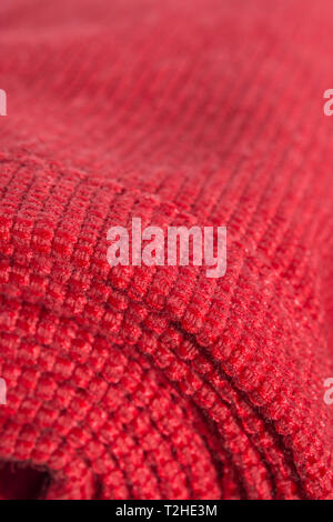 Close-up / extreme macro of orange polyester material with red stitched seam. Metaphor rolled up, on a roll, woven fabric edge. Stock Photo