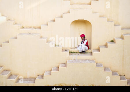 Man in Indian traditional clothing sitting in alcove on Panna Meena Ka Kund in Jaipur, India, Asia Stock Photo