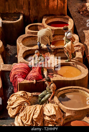 MOROCCO FES MEDINA THE CHOUARA TANNERY  HIDES IN VATS WITH COLOURED DYES AND SOME WORKERS PROCESSING THE LEATHER Stock Photo