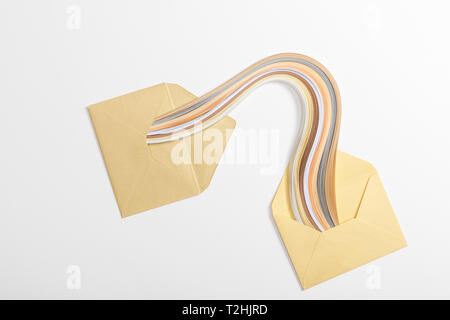 top view of yellow envelopes with multicolored rainbow on grey background Stock Photo