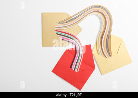 top view of yellow and red envelopes with multicolored rainbow on grey background Stock Photo