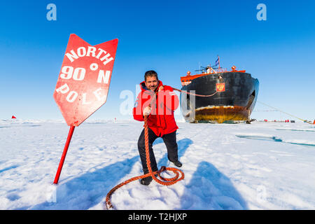 Man pretending to pull the Icebreaker '50 years of victory' on the North Pole, Arctic Stock Photo