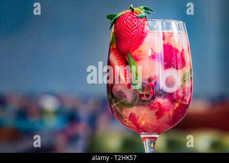 Glass of strawberry lemonade with lemon, ice cubes and several fresh ripe strawberries. Selective focus. Healthy summer drink Stock Photo