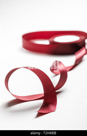 selective focus of silk wavy burgundy ribbon with spool on grey background Stock Photo