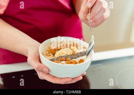 Close-up of woman's hand holding bowl of delicious oatmeal and spoon Stock Photo
