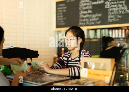 Young barista taking money from customer pay for beverage at coffee shop Stock Photo