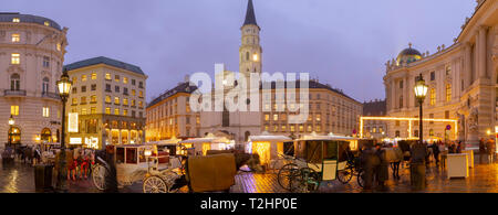 Christmas Market stalls and St. Michael Catholic Church in Michaelerplatz, Vienna, Austria, Europe Stock Photo