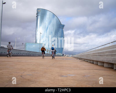 BARCELONA, SPAIN-MARCH 13, 2019: Bicyclists on the W Barcelona Hotel (Aka Hotel Vela or Sail Hotel) background Stock Photo