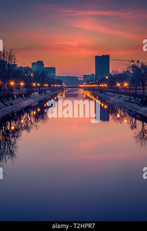 Vibrant cityscape shot early morning before sunrise in Bucharest with a river in the foreground and big buildings Stock Photo