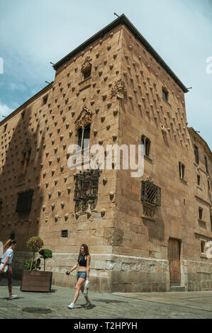 People in front of the Casa de las Conchas with facade adorned by shells at Salamanca. The city preserves many buildings of ancient Rome in Spain. Stock Photo