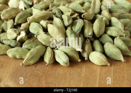 Pile of dry scattered unrefined cardamom seeds lying on wooden boards Stock Photo