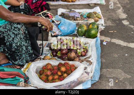 Galle, Sri Lanka - February 18th, 2019: Local sri lankan women selling Rambutan and Mangus (mangosteen) fruits sitting on the street in Galle, Sri Lan Stock Photo
