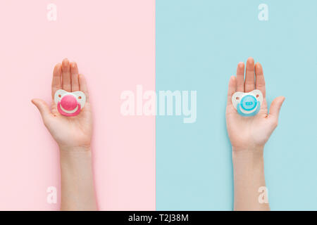 partial view of women holding pacifiers on blue and pink background with copy space Stock Photo